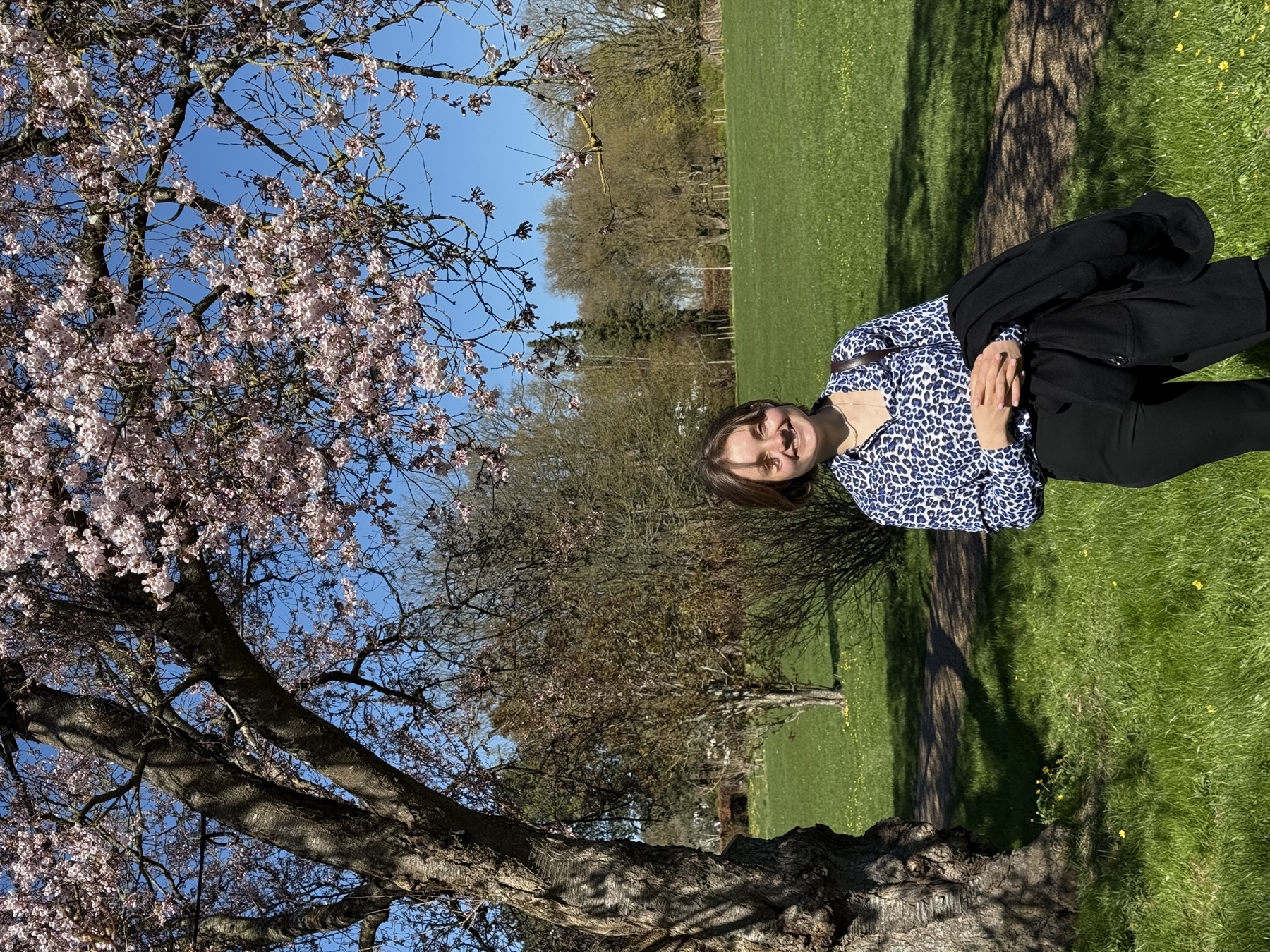 Alina laughing under a blossoming cherry tree on a bright spring day
