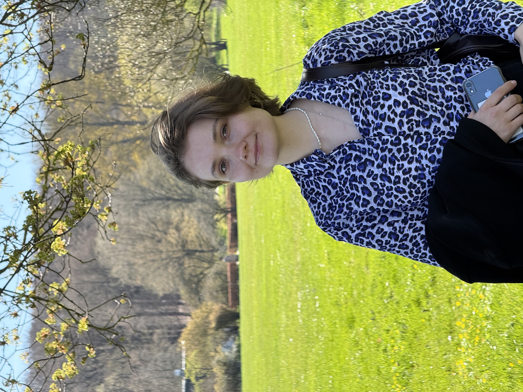 Portrait of Alina in a sunny park, in a blue leopard-print shirt, smiling